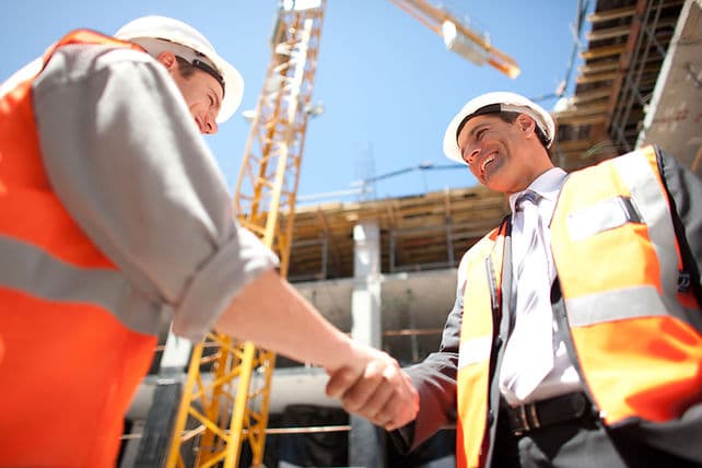 Two construction professionals shaking hands on a building site