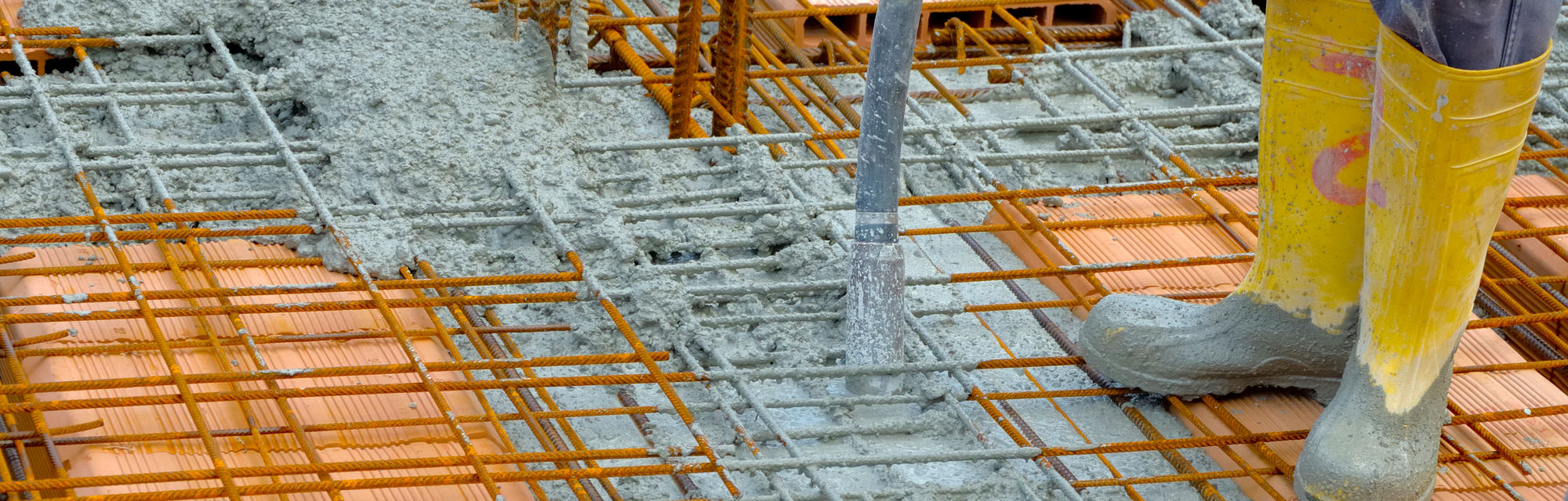 Fresh concrete poured over steel rebar mesh on a construction site